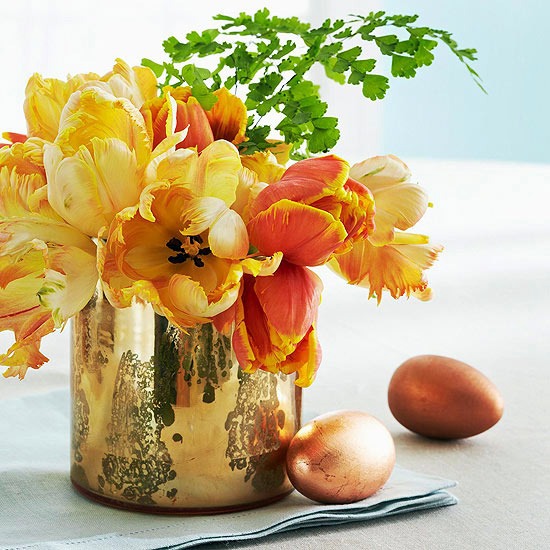 Gold plated, polished vase with flowers of yellow and orange spring