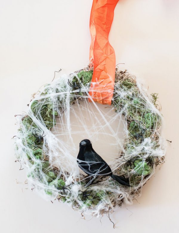 Welcome trick-or-treaters with a wreath of cobwebs, spiders and a black crow.