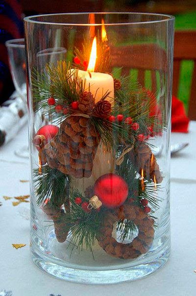 Wide glass vase with candle and Christmas decorative elements.