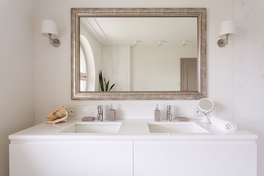 An elegant bathroom design with beautiful white double sink and vanity and lots of natural light. Pic by bayhomebuildersinc