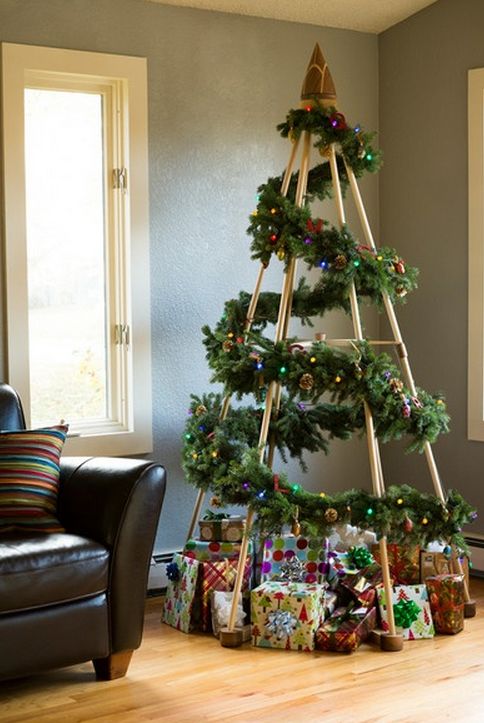 Chic Christmas tree made by wooden sticks and decorated with leaves and gifts.