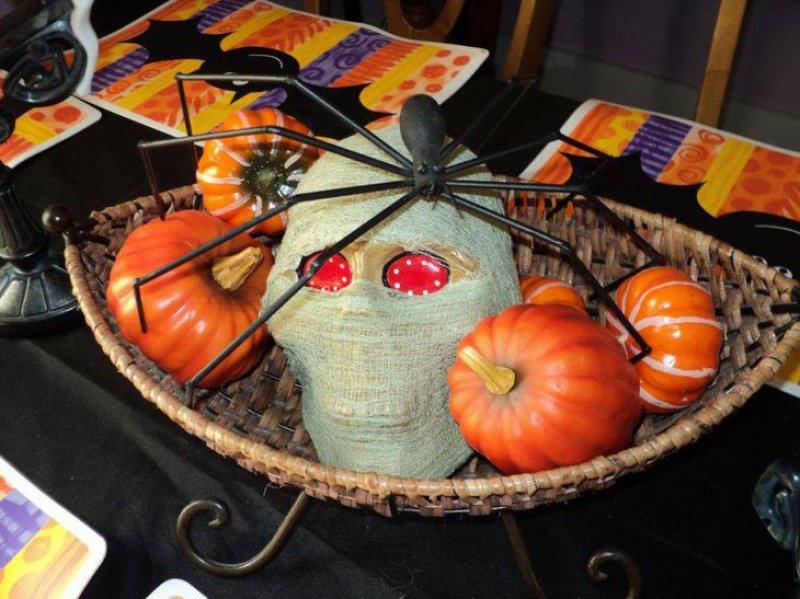 Wrapped skull with a black spider on top Halloween table centerpiece.