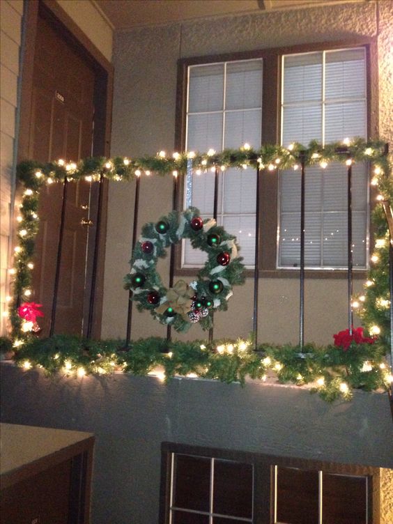 Railing decorated with garland clear lights and two poinsettias at corner of each end.